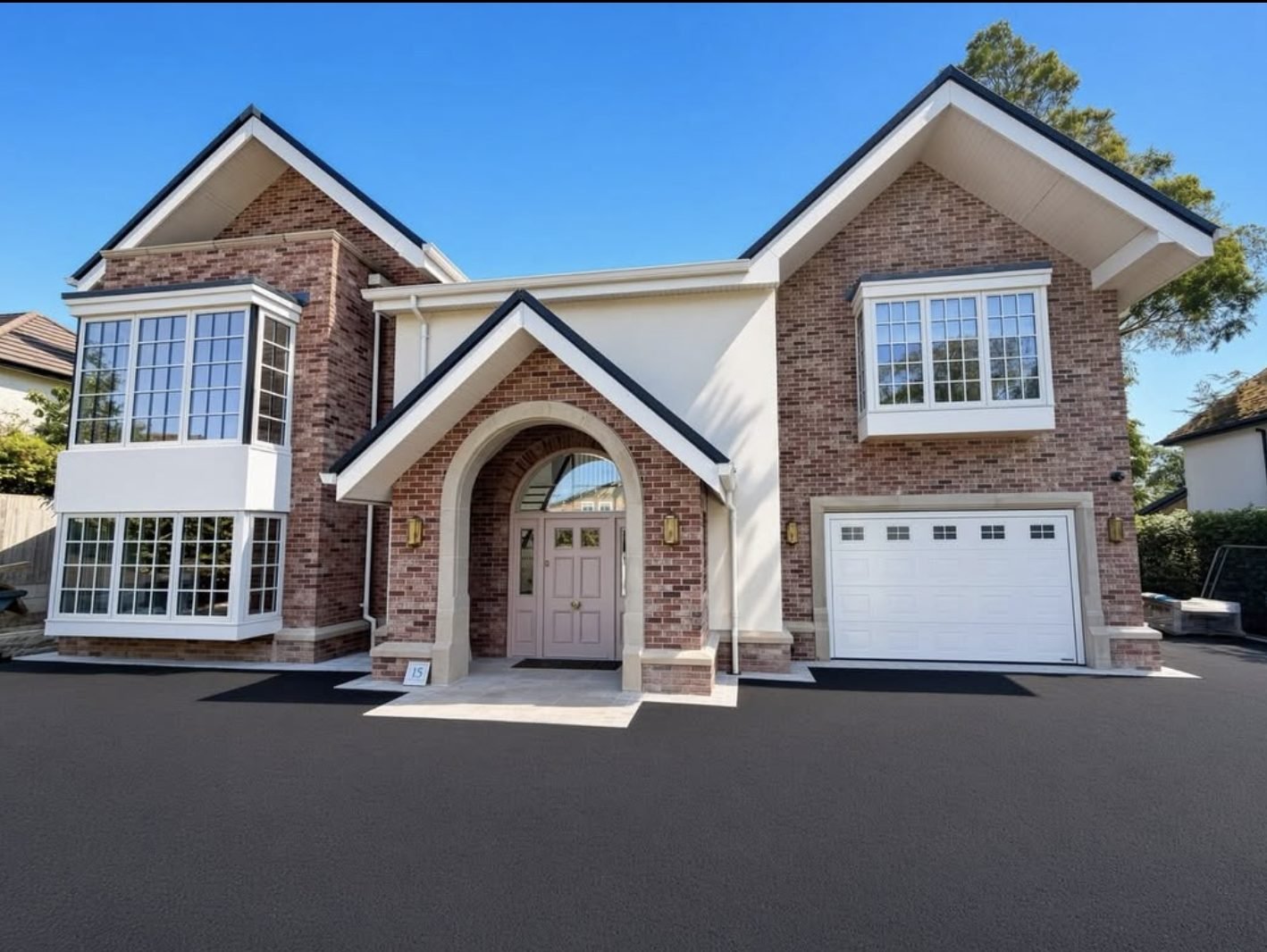 New house with cream render panels between red brick gables and a brick arch