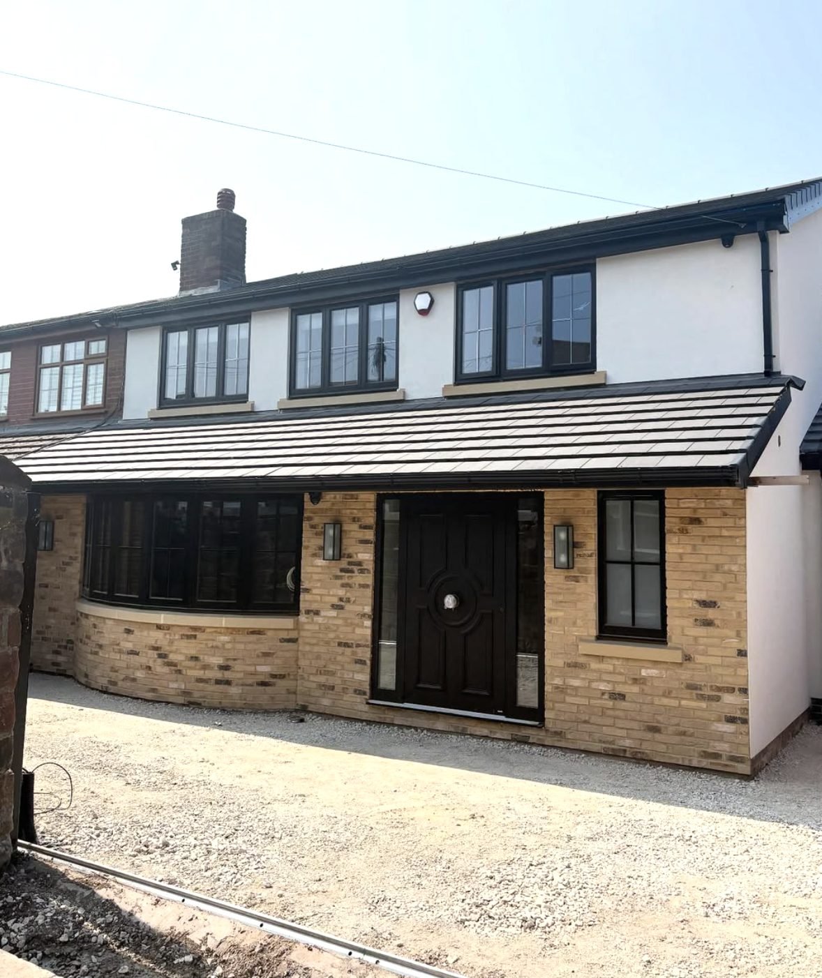 Semi-detached house with white render above a new buff brick front extension